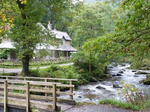 a house next to a river in front of a house at The Pack Horse Exmoor National Park Allerford Riverside Cottage & Apartments in Minehead