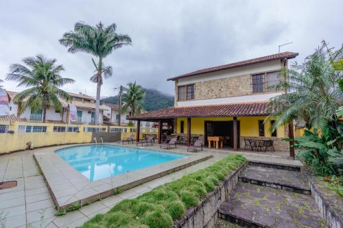 a villa with a swimming pool in front of a house at Pousada Recanto de Itacuruçá in Itacuruçá