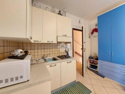 una cocina con armarios blancos y una puerta azul en Monolocale IL GRIFO, en Albisola Superiore