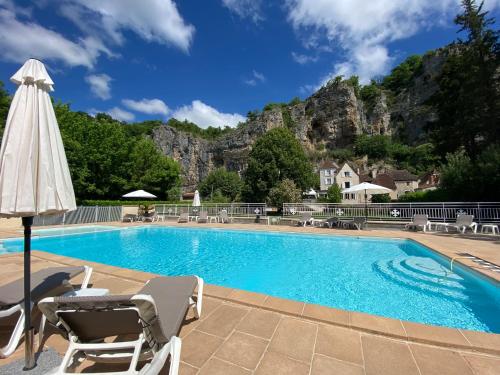 a swimming pool with chairs and an umbrella at Logis Hôtels - Hôtel Restaurant Domaine Les Falaises in Martel