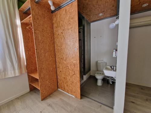 a bathroom with a wooden door and a toilet at La Posada de El Chaflán in Madrid