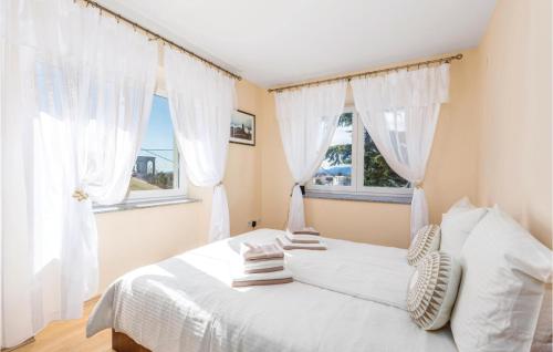 a bedroom with a white bed with two windows at Beautiful Home In Kastav With Kitchen in Kastav