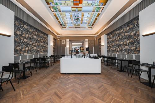 un salon avec des tables et des chaises dans une pièce dotée d'un plafond dans l'établissement Hotel Louisa, à Ostende