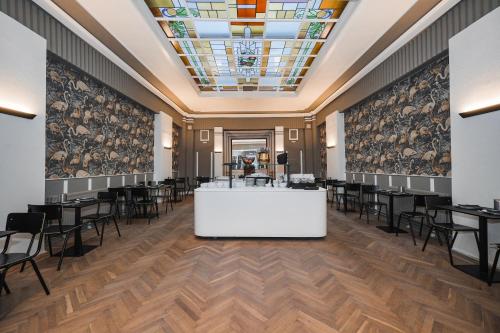 a salon with tables and chairs in a room with a ceiling at Hotel Louisa in Ostend