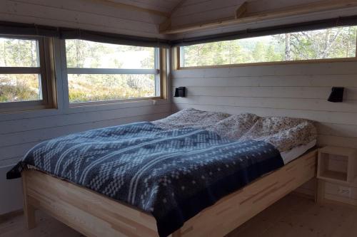 a bed in a room with two windows at Myrullen - Cabin at Sørbølfjellet in Flå