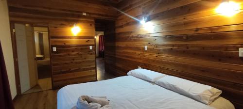 a bedroom with a wooden wall with a bed in it at Cabañas Santa Maria Huife in Pucón