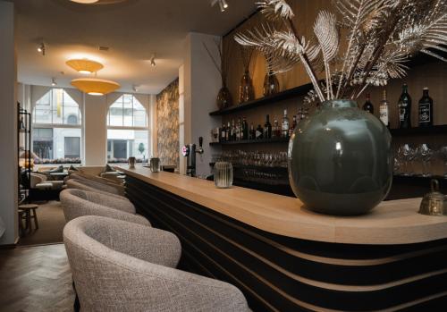 een bar met stoelen en een grote vaas op de toonbank bij Hotel Louisa in Oostende