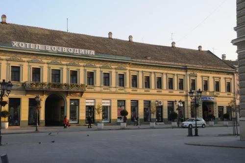 a large yellow building with a car parked in front of it at Hotel Vojvodina in Novi Sad