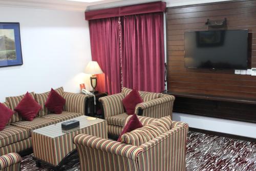 a hotel room with couches and a flat screen tv at Carawan Al Khaleej Hotel Olaya in Riyadh