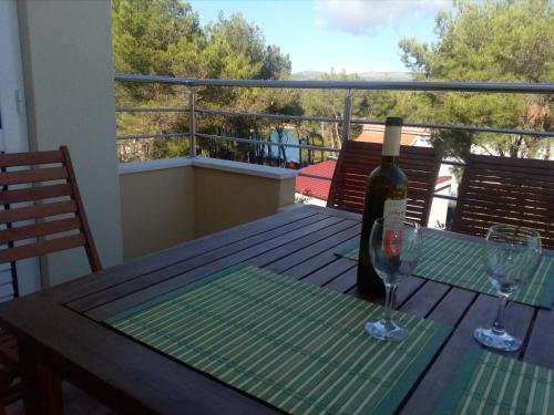 a bottle of wine and two glasses on a table on a balcony at Apartments Mimose in Milna