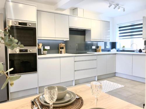 a kitchen with white cabinets and a table with wine glasses at Spacious En-suite Private Double Bedroom in Oxford