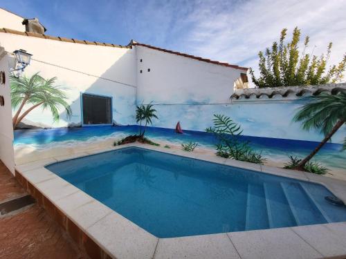 een zwembad voor een gebouw met een muurschildering van de oceaan bij Casa en pueblo con piscina cerca de Córdoba in Encinarejo De Córdoba