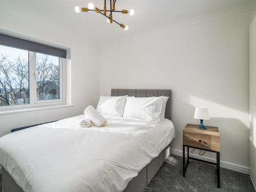 a bedroom with a white bed and a window at Pass the Keys Stylish 4 Bedroom Home with Parking in Borehamwood in Borehamwood
