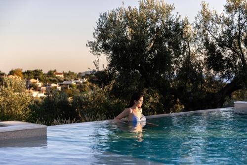 a woman is sitting in a swimming pool at Kastri Elia Suites in Nikiti