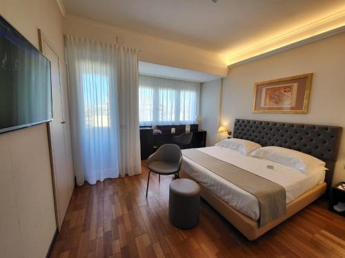 a bedroom with a large bed and a chair at Hotel Plaza in Pescara