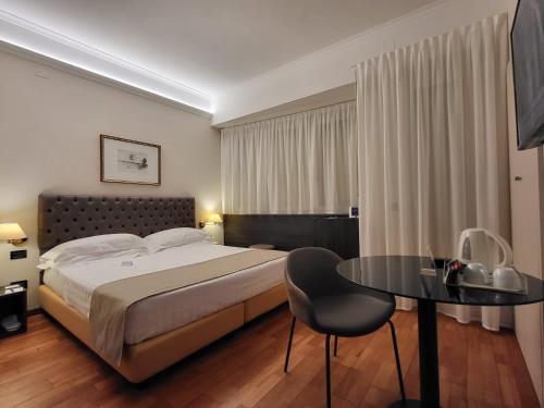 ein Hotelzimmer mit einem Bett, einem Tisch und einem Stuhl in der Unterkunft Hotel Plaza in Pescara