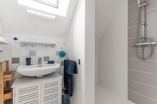 ein weißes Bad mit einem Waschbecken und einer Dusche in der Unterkunft Chez Merlin in Larmor-Baden