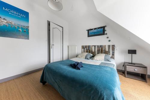 - une chambre avec un grand lit et une couverture bleue dans l'établissement Chez Merlin, à Larmor-Baden