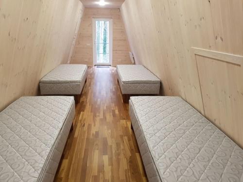 three beds in a room with wooden floors at Puraviku puhkemaja in Elbiku