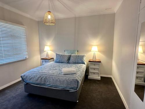 a bedroom with a bed and two night stands at Beach Shack Bunbury in Bunbury