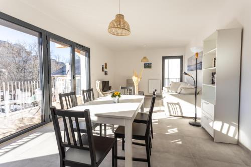 une cuisine et une salle à manger avec une table et des chaises blanches dans l'établissement Au Calme des Sommets - Vue montagne, à Embrun