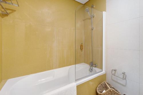 特羅亞的住宿－Apartamento T1 - Tróia Resort，一间带浴缸和淋浴的浴室,配有玻璃门