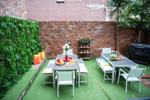 a patio with two tables and chairs and a brick wall at Liverpool Georgian Town House Catharine St in Liverpool