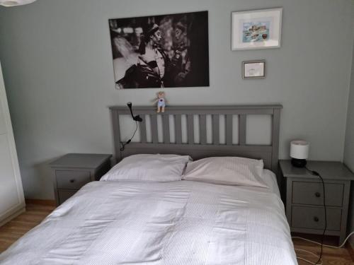 1 cama con sábanas blancas y 2 mesitas de noche en un dormitorio en Aquamarina Międzyzdroje, en Międzyzdroje