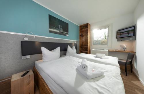 um quarto com uma grande cama branca com toalhas em T3 Budget Berlin Hennigsdorf em Hennigsdorf