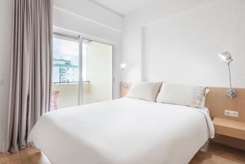 a white bedroom with a large bed and a window at Equador Superior Suites by Olala Homes in Cascais