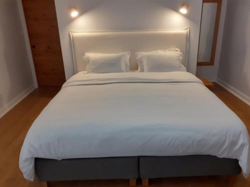 a large white bed with white sheets and pillows at La Vieille Maison aux Canards in Neuvic-Entier
