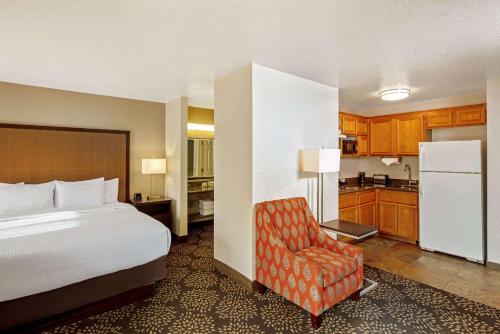 1 dormitorio con 1 cama y 1 silla y cocina en La Quinta by Wyndham Las Vegas RedRock/Summerlin en Las Vegas