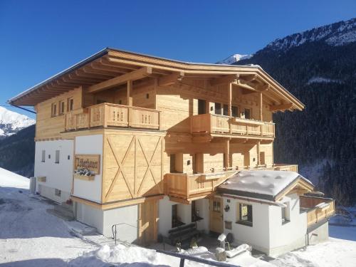 a large wooden building in the snow in the mountains at Landhaus Löberbauer in Tux