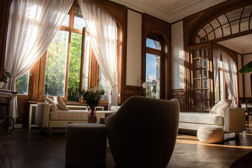 a living room filled with furniture and large windows at La Villa Barbieux in Roubaix
