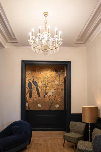 a chandelier in a room with a painting on the wall at La Villa Barbieux in Roubaix