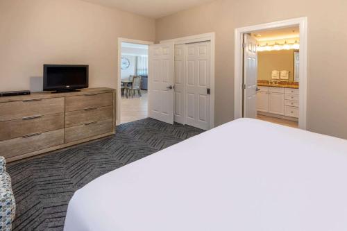 a bedroom with a bed and a flat screen tv at Escapes! To The Shores Orange Beach, A Ramada by Wyndham in Orange Beach