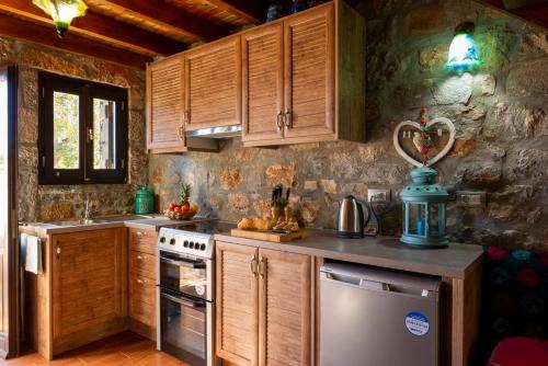 uma cozinha com armários de madeira e um forno com placa de fogão em Carob Cottage em Elounda