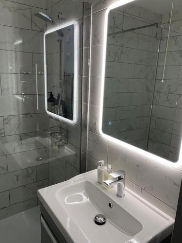 Baño blanco con lavabo y espejo en Port Pour Deux, en Portrush