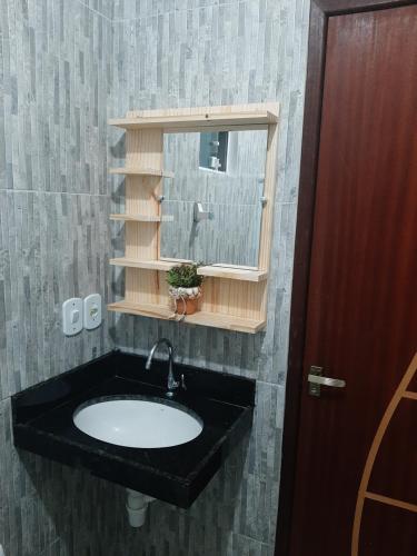 ein Waschbecken mit einem Spiegel und einem Fenster in der Unterkunft Casa em São Miguel dos Milagres in São Miguel dos Milagres