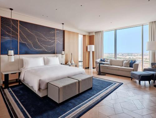 een slaapkamer met een groot bed en een woonkamer bij Grand Hyatt Kuwait in Koeweit