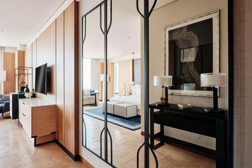a living room with a mirror and a bedroom at Grand Hyatt Kuwait in Kuwait