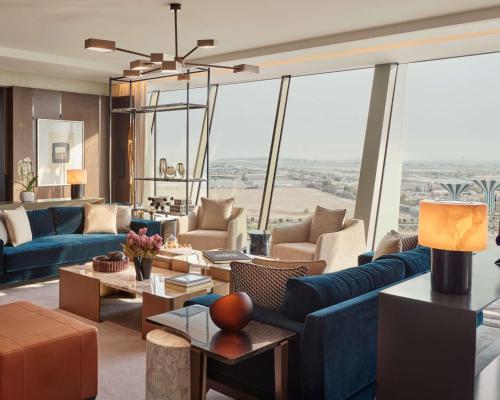 a living room with blue couches and tables and large windows at Grand Hyatt Kuwait in Kuwait
