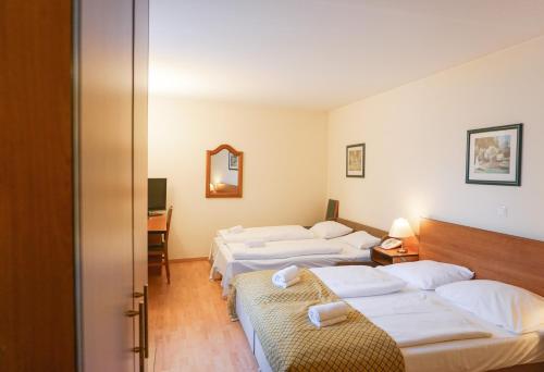 Habitación de hotel con 3 camas y espejo en Hotel Deutschmeister, en Viena