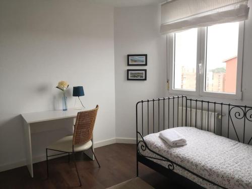 een slaapkamer met een bed, een bureau en een raam bij Spacious and light flat with beautiful views in Santander