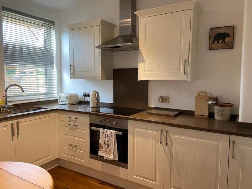 a kitchen with white cabinets and a stove top oven at Lovely little house in Yarrowford - Yarrow Valley in Broadmeadows