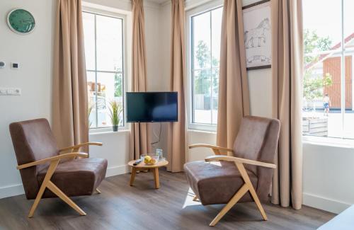a living room with two chairs and a tv at Familie Resort Molenwaard in Ottoland