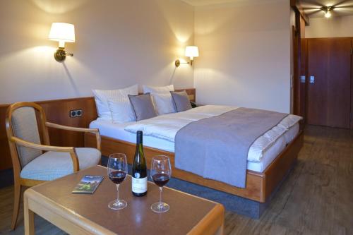 Käfernberg - Weinhotel في آلتسناو اين اونترفرانكن: غرفة في الفندق بها سرير وكأسين من النبيذ