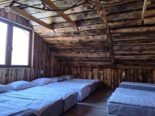 two beds in a room with wooden walls and windows at Agroturystyka siedlisko stodoła w stylu boho, imprezy okolicznościowe, 