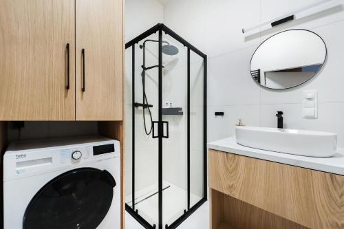 a bathroom with a washing machine and a sink at Sol Marina Resort Wyspa Sobieszewska I - LoftAffair Collection in Wiślinka