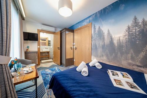 a bedroom with a blue bed with a painting on the wall at Serce Tatr Residence Zakopane - blisko Krupówek in Zakopane